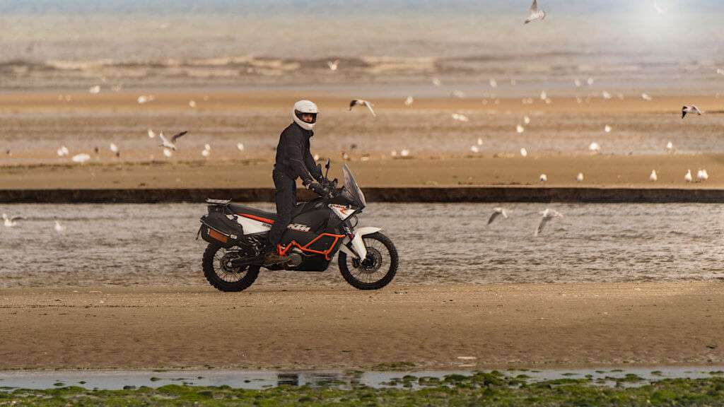 Man riding a KTM on a beach