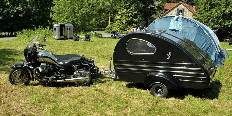 Black teardrop camper connected to a motorcycle