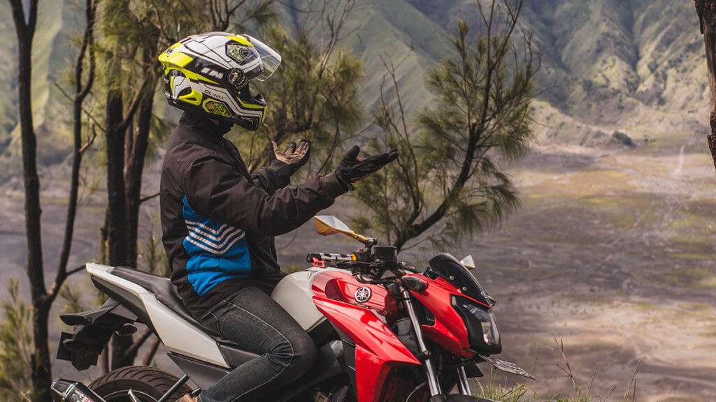 Person on red motorcycle with their hands out in front