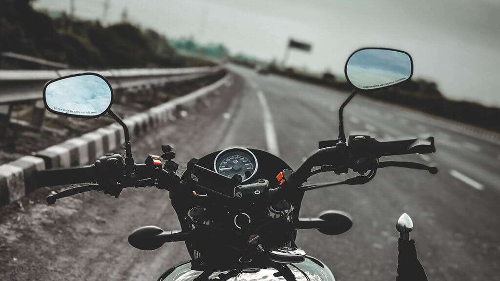 Close-up of motorcycle dashboard with mirrors stopped on the side of the road