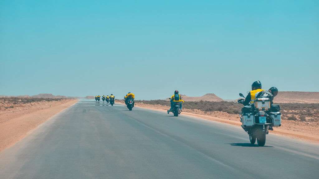 Group of motorcycle riders spread out on a desert highway