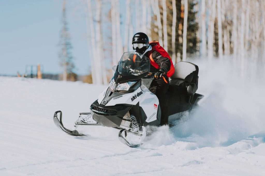 Snowmobile speeding on snow near treeline