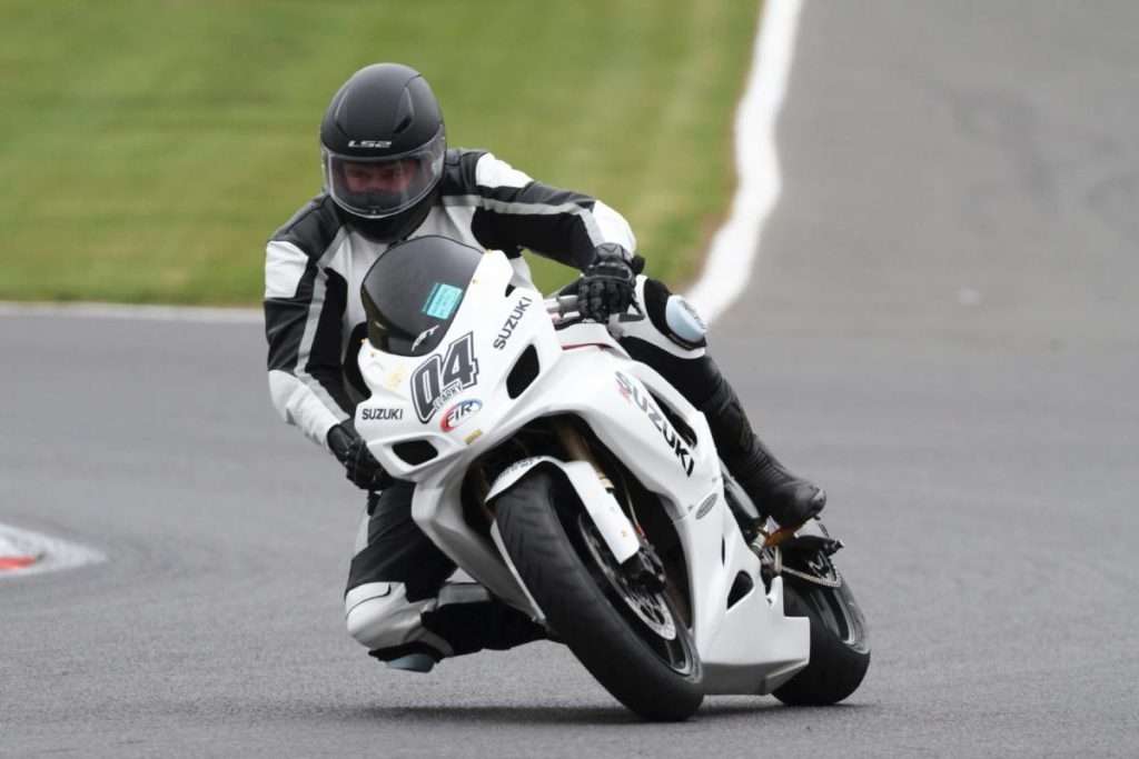 White racing motorcycle with rider wearing full body equipment