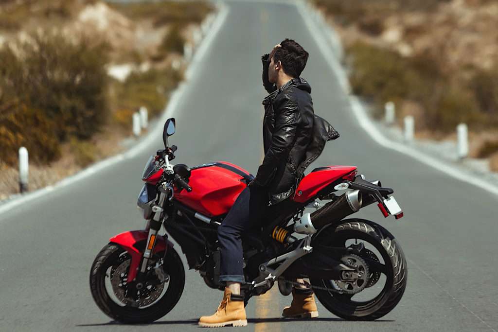 Man on red motorcycle wearing a black jacket