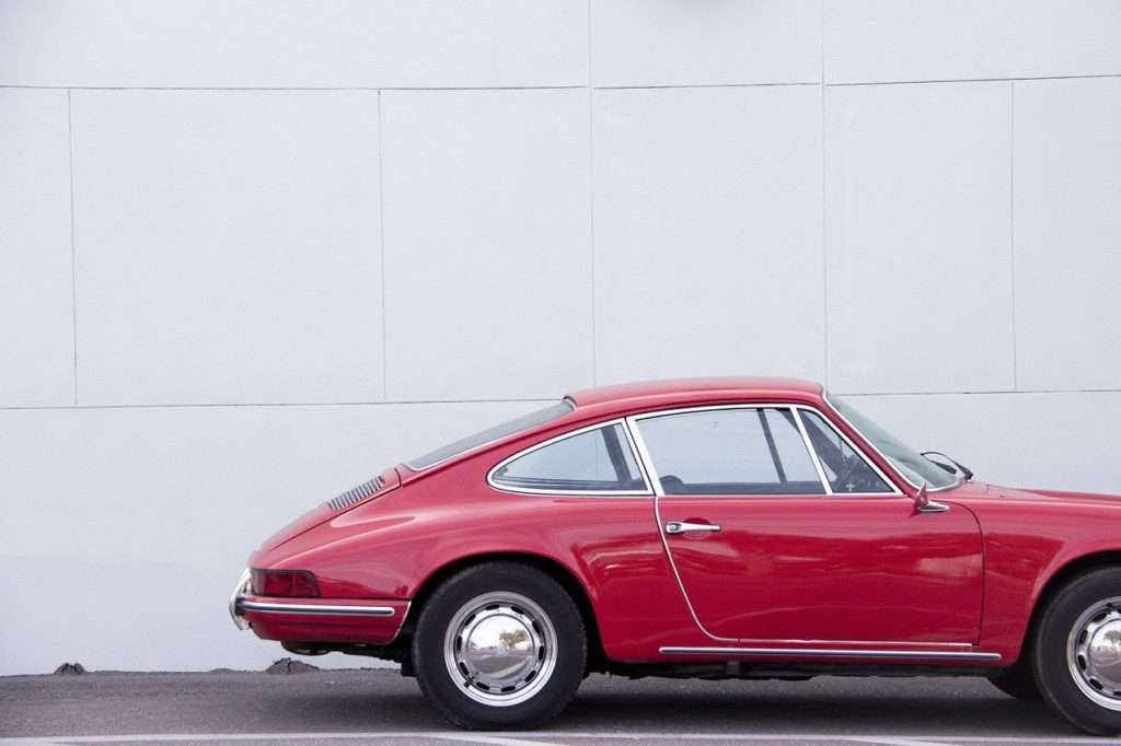 Old red car in front of a white wall