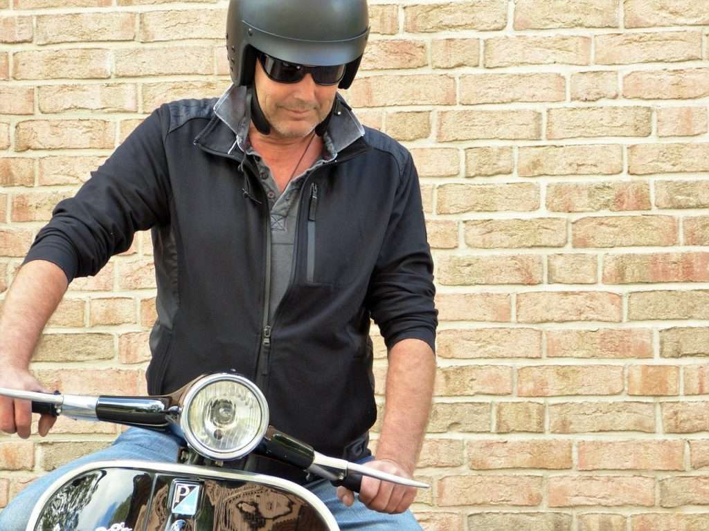 Man with hands on black vespa handlebar