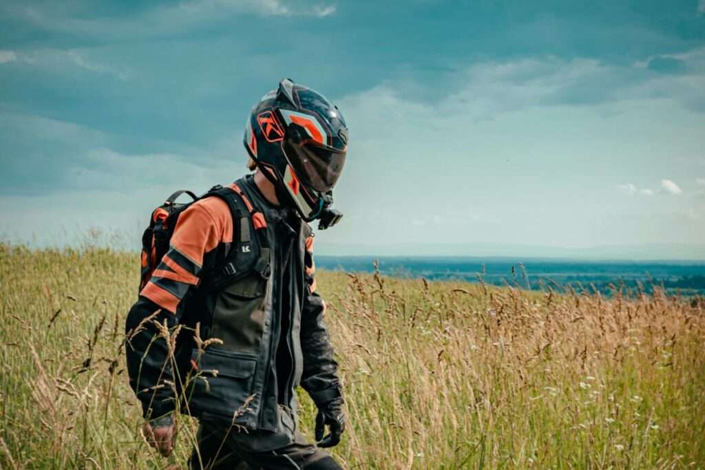 Man with motorcycle jacket and helmet on walking in a field