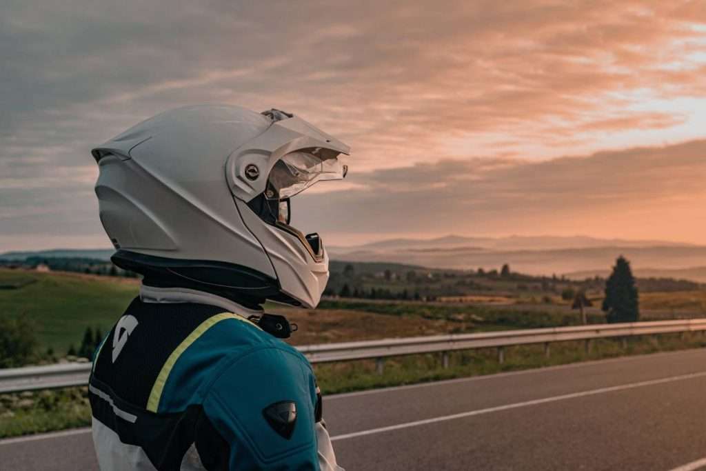 Person wearing a white motorcycle helmet at sunset