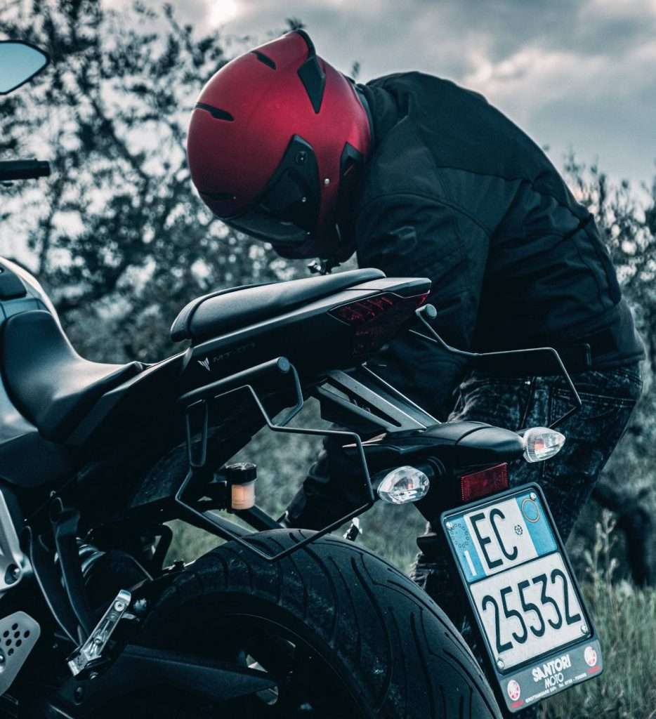 Motorcycle rider with red helmet checking motorcycle chain