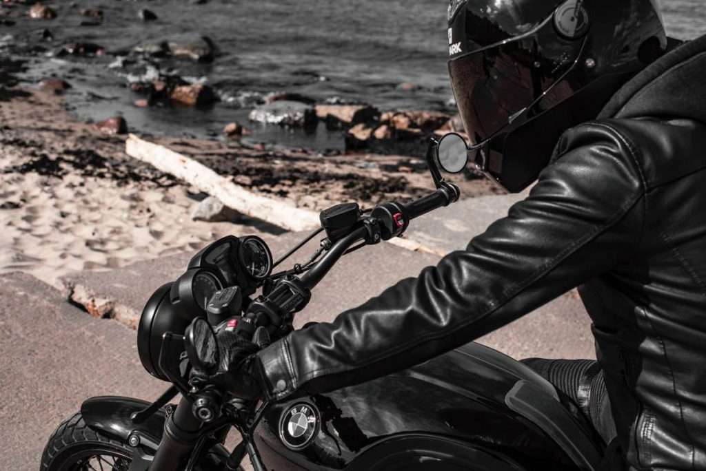 Man wearing a black motorcycle jacket on a black BMW