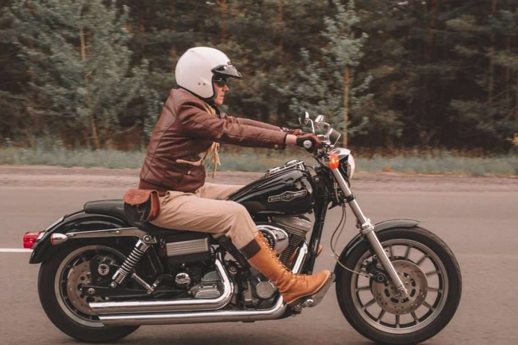 Man with white open-face helmet riding a black motorcycle