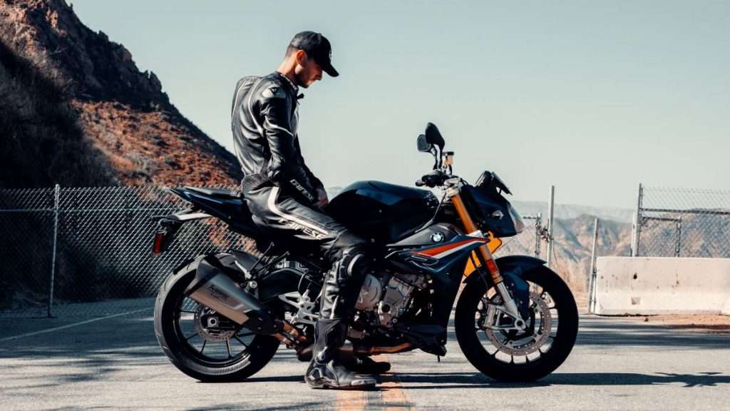 Man on a BMW motorcycle wearing black Dainese motorcycle jacket and pants