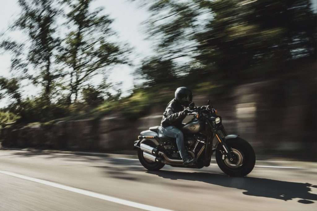 Rider with black jacket and helmet on a gray Harley-Davidson